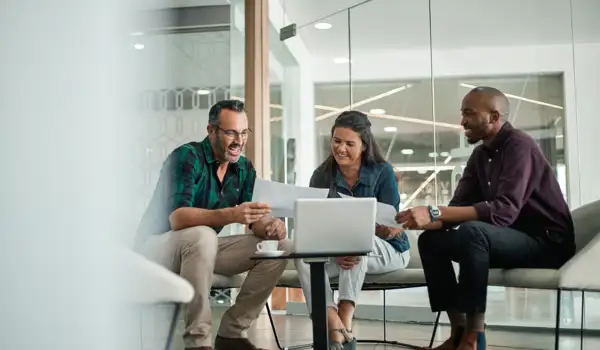 Group of happy people sitting down looking at a paper