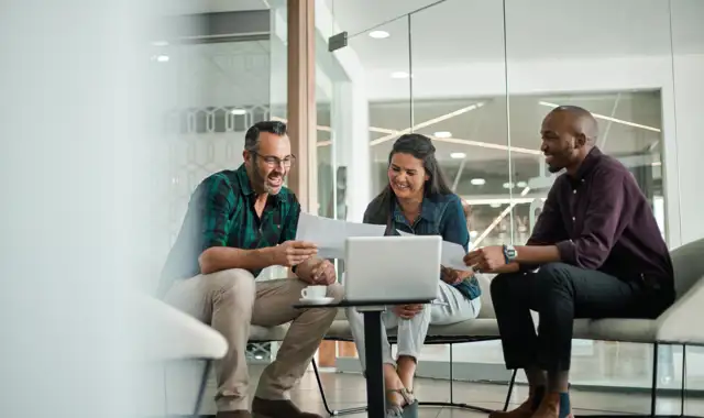 Group of happy people sitting down looking at a paper