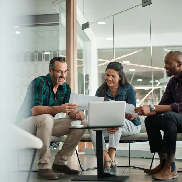 Group of happy people sitting down looking at a paper