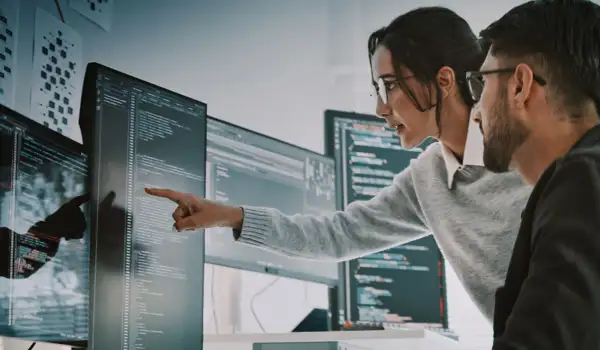 Woman pointing at screen while man looks a the same screen