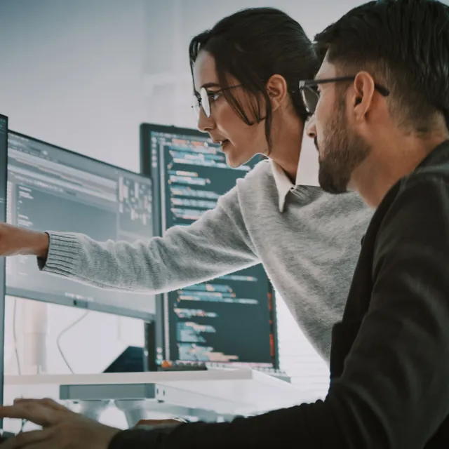 Woman pointing at screen while man looks a the same screen