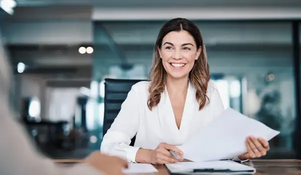 Woman smiling in a office holding a piece of paper