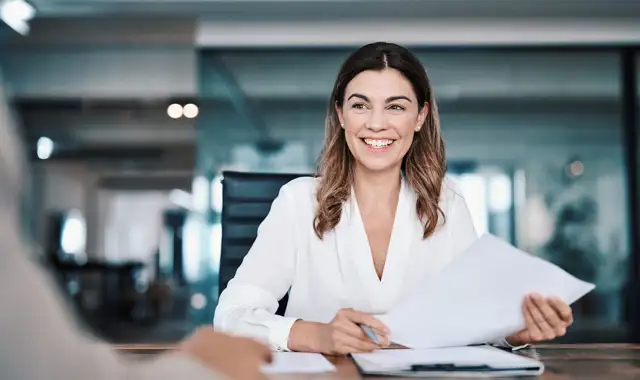 Woman smiling in a office holding a piece of paper