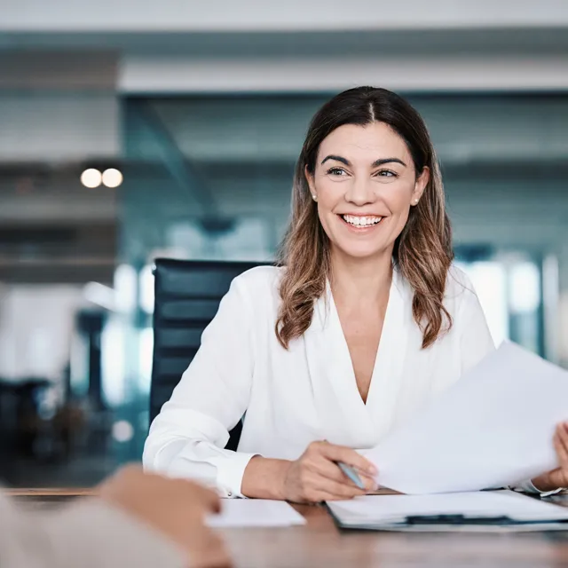 Woman smiling in a office holding a piece of paper