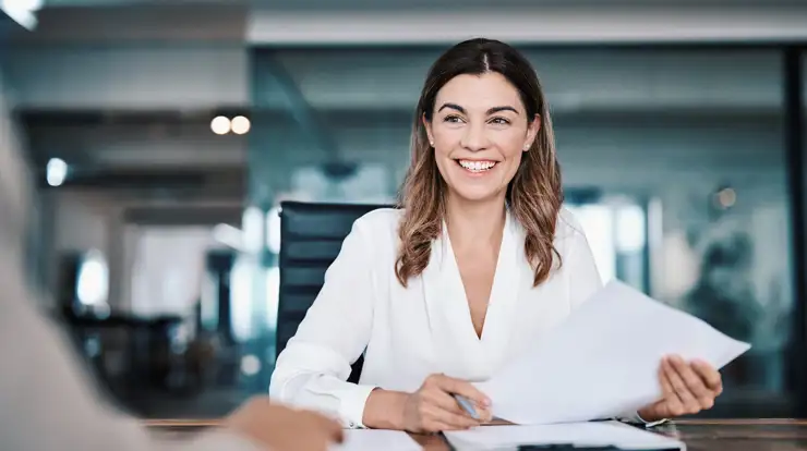 Woman smiling in a office holding a piece of paper