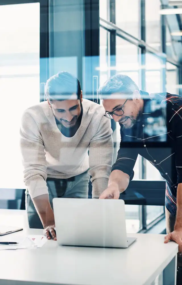 Two men smiling pointing at screen