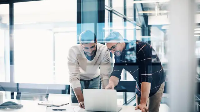 Two men smiling pointing at screen