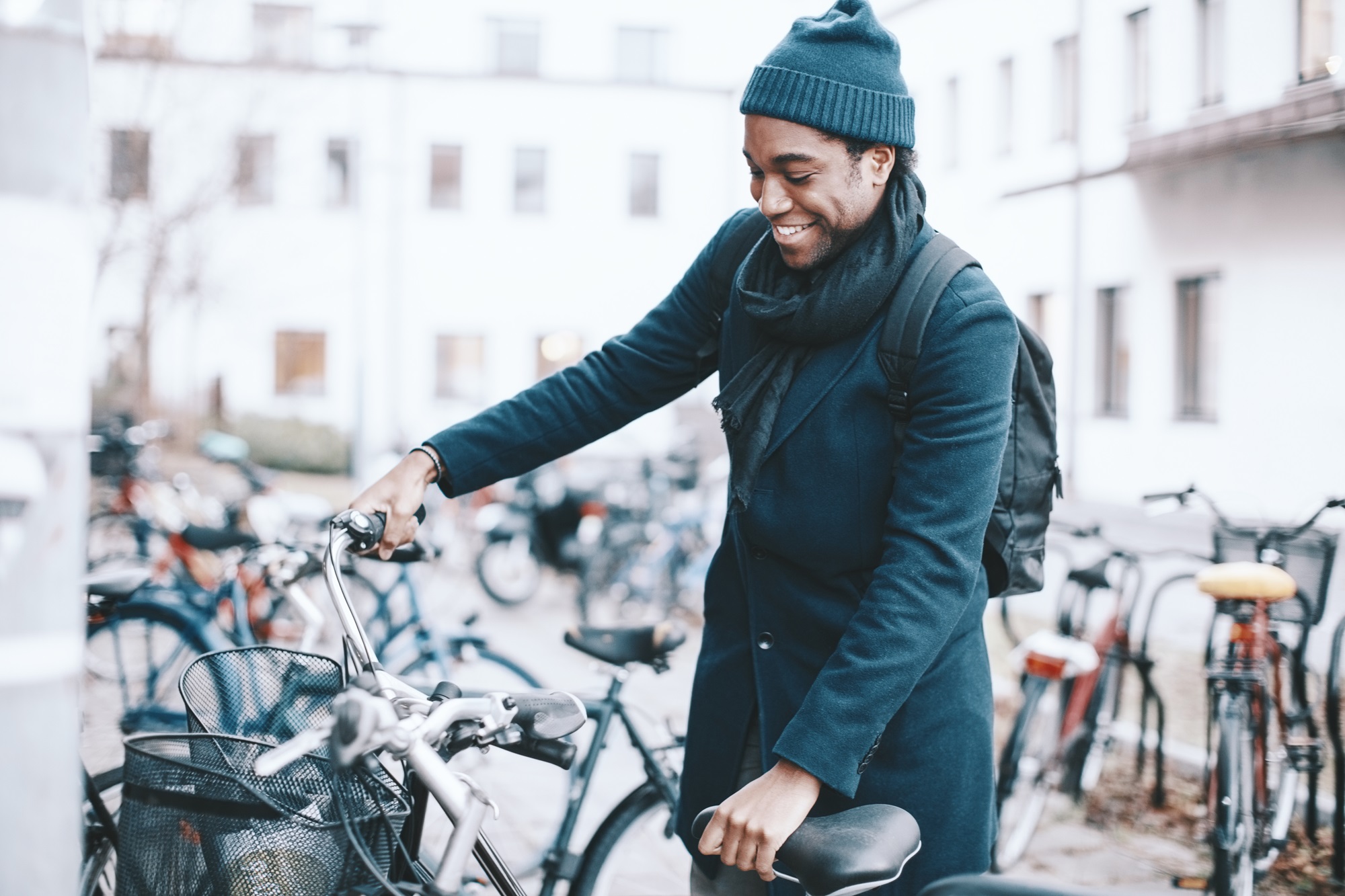 A man parking his bike at an apartment complex.