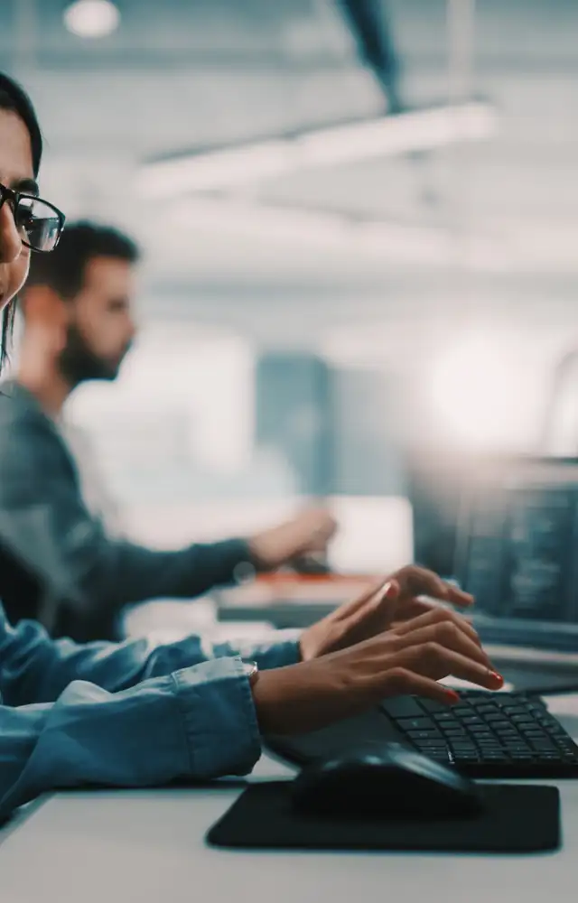 Woman with glasses writing on a keyboard