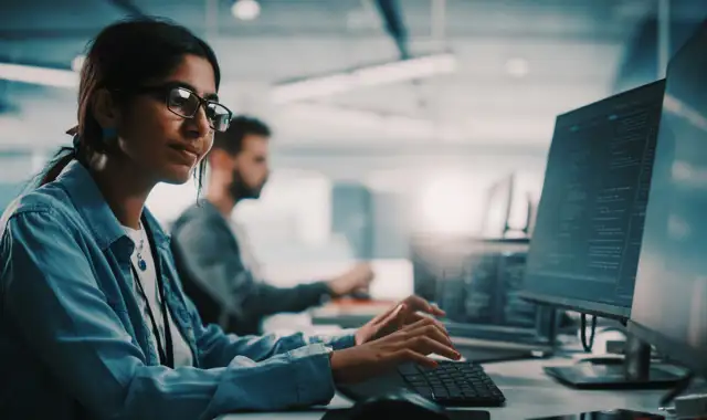 Woman with glasses writing on a keyboard