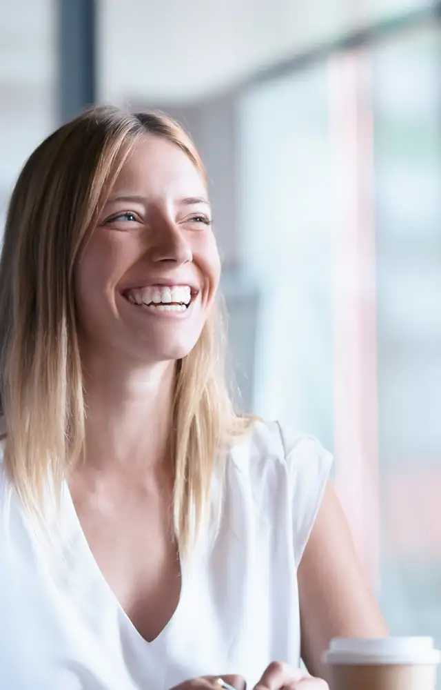 Woman with coffee laughing sitting in business environment