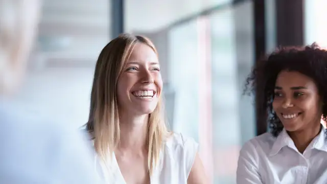 Woman with coffee laughing sitting in business environment