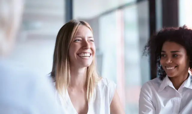 Woman with coffee laughing sitting in business environment