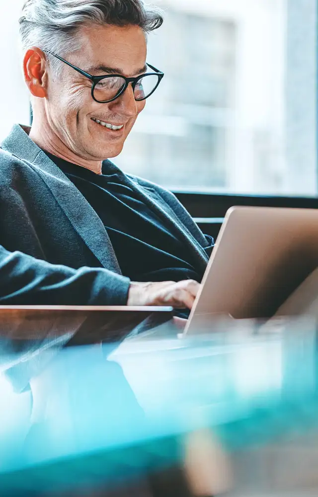 Man sitting and typing on a computer while smiling