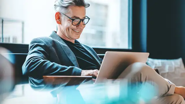 Man sitting and typing on a computer while smiling